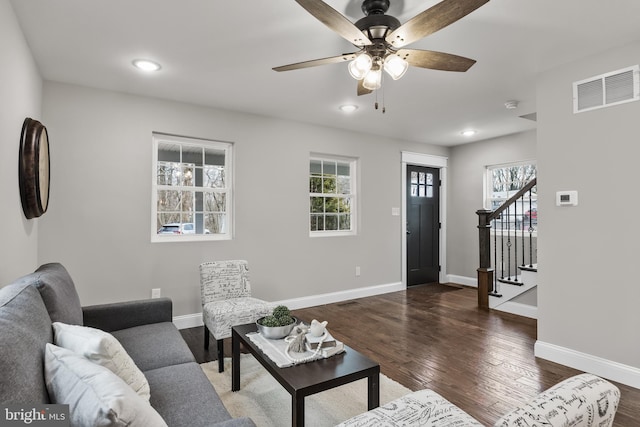 living area featuring baseboards, stairs, visible vents, and dark wood finished floors