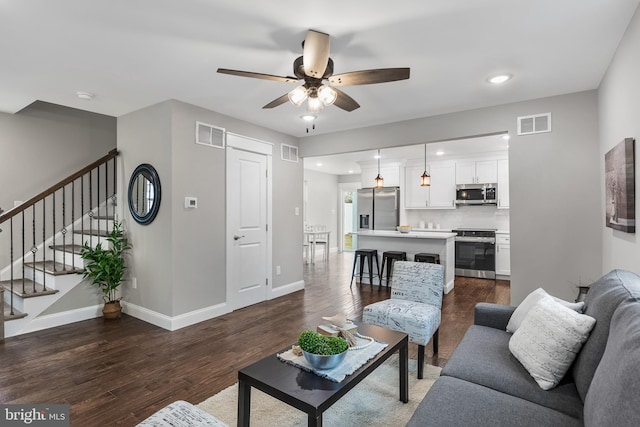 living room with visible vents, dark wood finished floors, and stairway