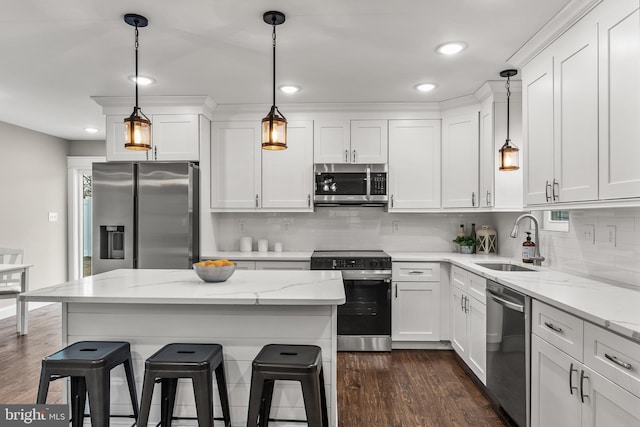 kitchen featuring hanging light fixtures, appliances with stainless steel finishes, white cabinets, and a sink