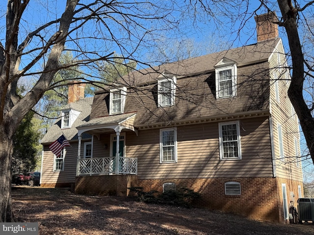 view of front of home with a chimney, a shingled roof, covered porch, crawl space, and central AC