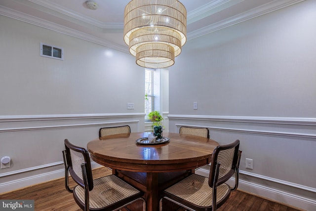 dining area featuring dark wood-style floors, visible vents, a notable chandelier, and ornamental molding