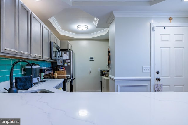 kitchen with decorative backsplash, ornamental molding, light stone countertops, stainless steel appliances, and a sink