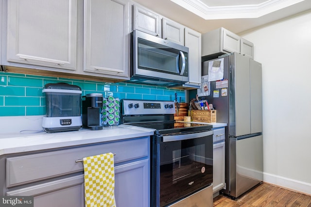 kitchen featuring baseboards, appliances with stainless steel finishes, light wood-style flooring, and decorative backsplash