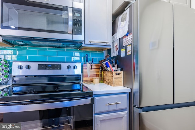 kitchen with appliances with stainless steel finishes, white cabinetry, and tasteful backsplash