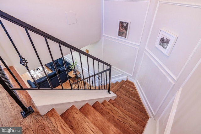 staircase with a decorative wall and wood finished floors