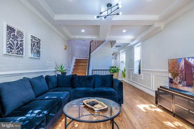 living area with coffered ceiling, stairway, wood finished floors, crown molding, and a decorative wall