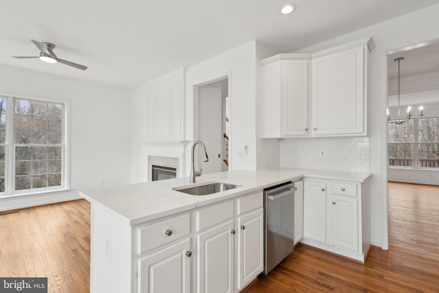 kitchen featuring a healthy amount of sunlight, a premium fireplace, a sink, dishwasher, and ceiling fan with notable chandelier