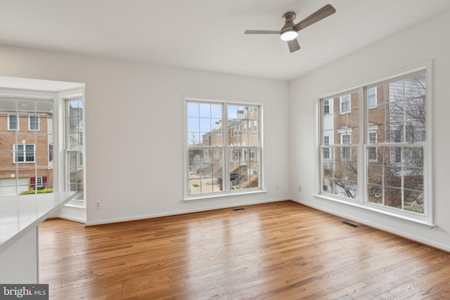 unfurnished dining area featuring visible vents, baseboards, wood finished floors, and a ceiling fan