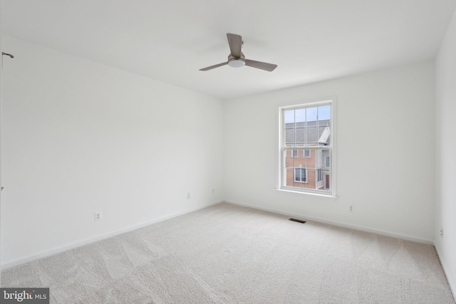 carpeted spare room featuring visible vents, baseboards, and a ceiling fan