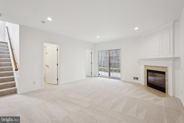 unfurnished living room featuring stairway, baseboards, recessed lighting, a high end fireplace, and light carpet