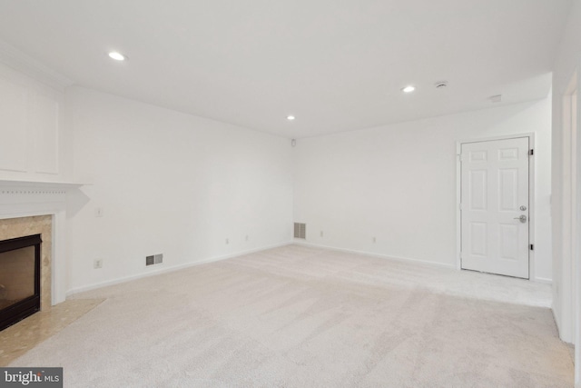 unfurnished living room with a high end fireplace, visible vents, recessed lighting, and light carpet