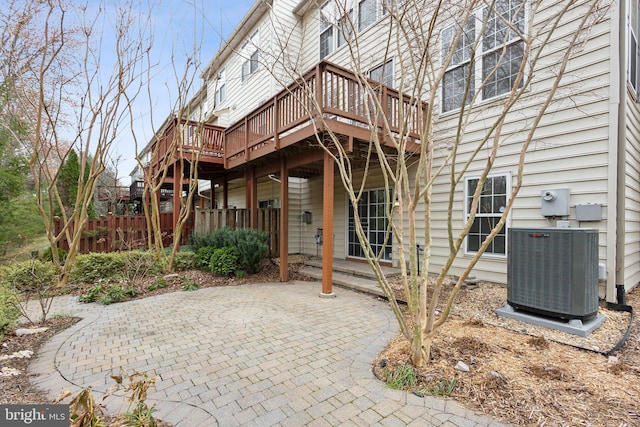 exterior space with a wooden deck, fence, central AC unit, and a patio area