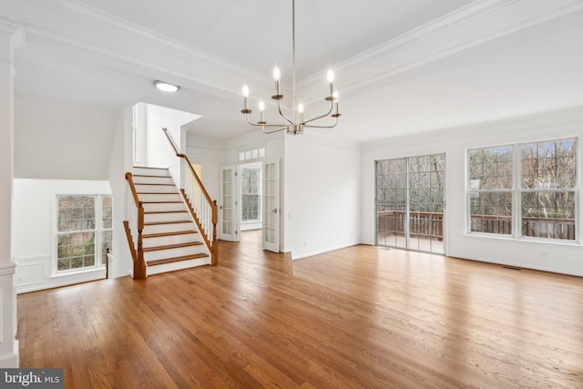 unfurnished living room with stairs, crown molding, a notable chandelier, and wood finished floors