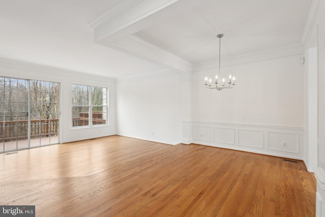 unfurnished room with crown molding, an inviting chandelier, and wood finished floors