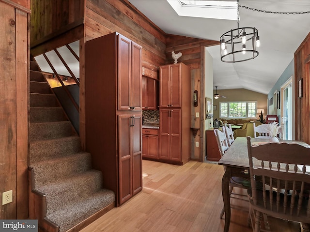 47 Timberline Dr, Lost River, WV 26810 - dining room featuring lofted ceiling, stairway, light wood-style flooring, a chandelier, and wood walls