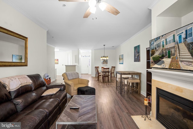 living room featuring a fireplace with flush hearth, crown molding, baseboards, and wood finished floors