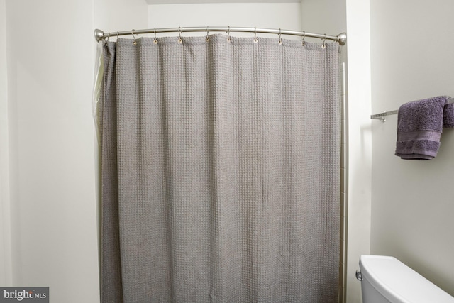 bathroom with a shower with shower curtain and toilet