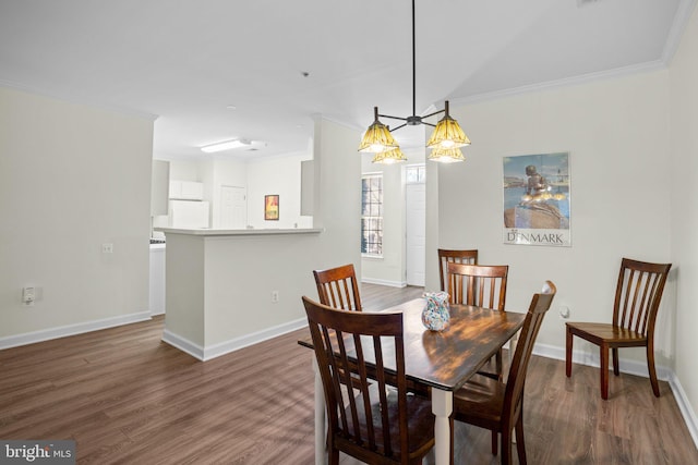 dining space featuring baseboards, wood finished floors, and crown molding