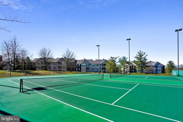 view of tennis court with community basketball court, fence, and a residential view