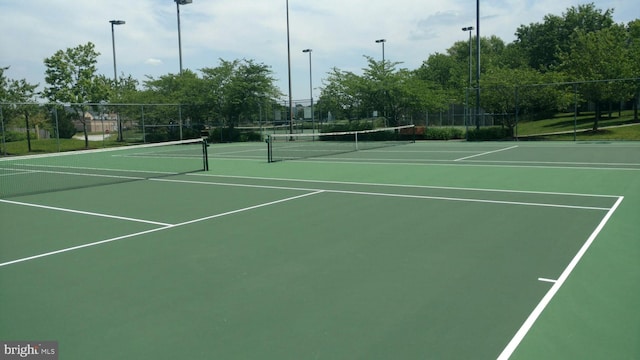 view of tennis court with community basketball court and fence