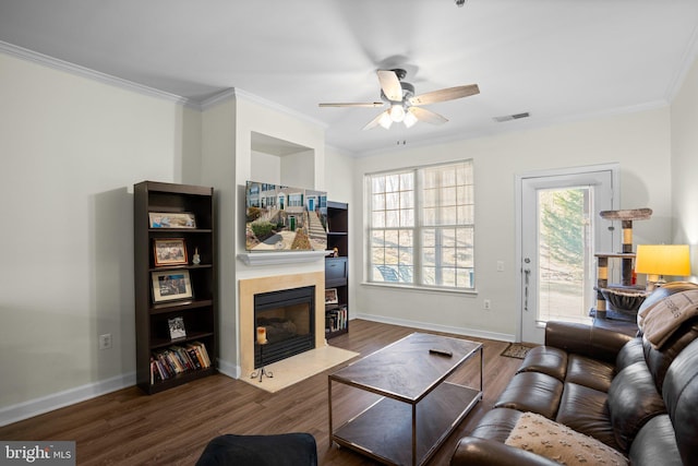 living room with a healthy amount of sunlight, wood finished floors, visible vents, and crown molding