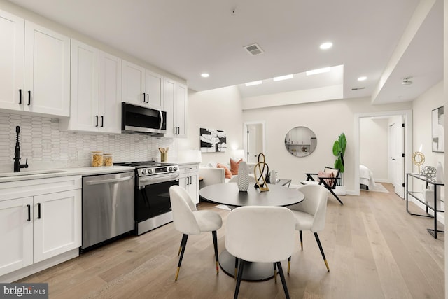 kitchen featuring stainless steel appliances, light countertops, a sink, and white cabinetry