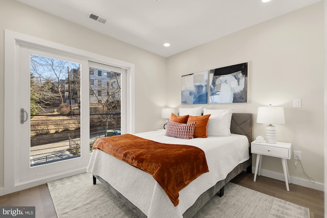 bedroom with visible vents, multiple windows, and wood finished floors