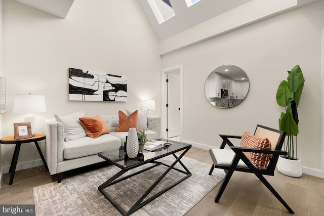 living area with baseboards, high vaulted ceiling, and light wood-style floors