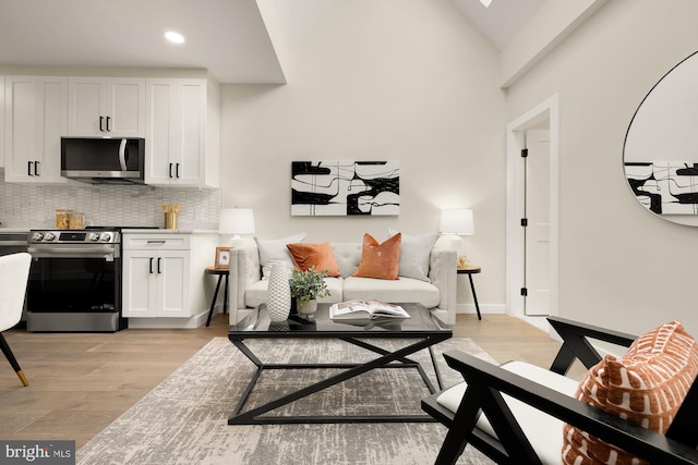 living room with vaulted ceiling, baseboards, light wood-style flooring, and recessed lighting