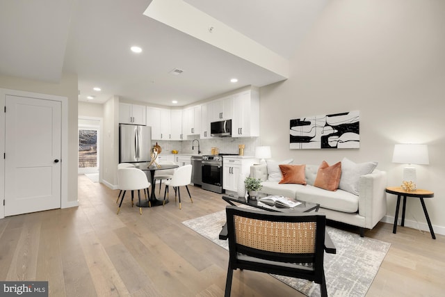 living room with light wood-style flooring, visible vents, baseboards, and recessed lighting