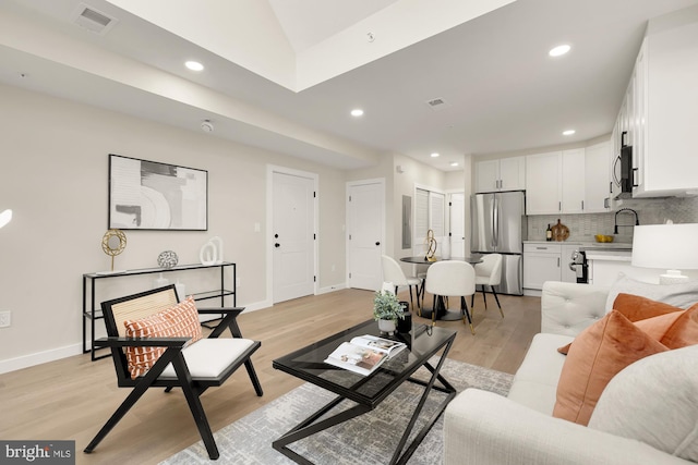 living room featuring light wood-type flooring, baseboards, visible vents, and recessed lighting