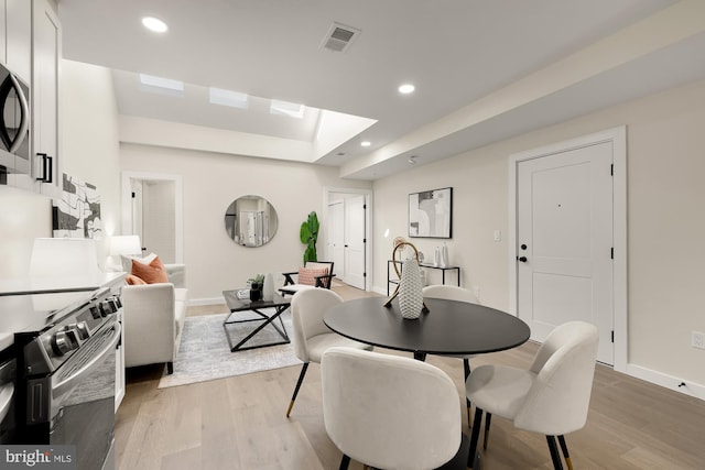 dining room featuring baseboards, light wood-style flooring, visible vents, and recessed lighting