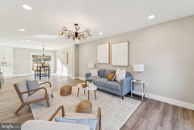 living room with baseboards, light wood-style floors, and a notable chandelier