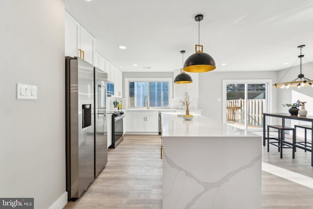 kitchen featuring a sink, a kitchen island, white cabinetry, appliances with stainless steel finishes, and light wood-type flooring