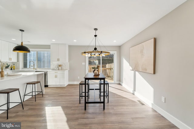 dining space featuring light wood-style floors, baseboards, visible vents, and a wealth of natural light