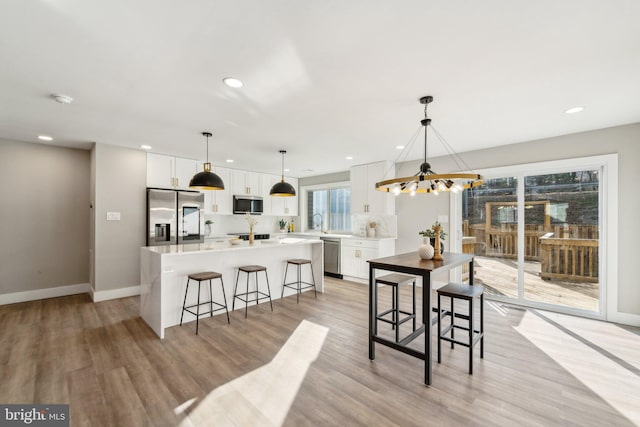 dining space with light wood finished floors, recessed lighting, and baseboards