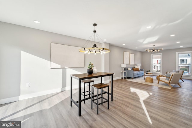 dining room with light wood-type flooring, an inviting chandelier, baseboards, and recessed lighting