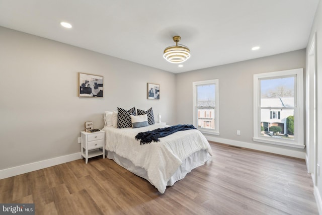 bedroom featuring baseboards, wood finished floors, and recessed lighting