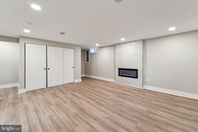 finished basement with recessed lighting, baseboards, a fireplace, and light wood finished floors