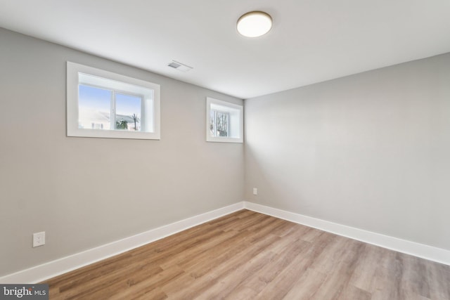 unfurnished room featuring baseboards, visible vents, and wood finished floors