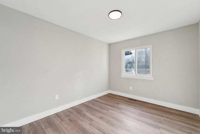 empty room featuring visible vents, baseboards, and wood finished floors