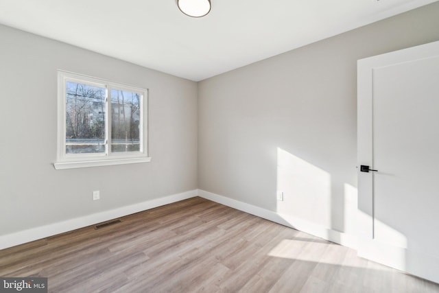 unfurnished room with baseboards, visible vents, and wood finished floors