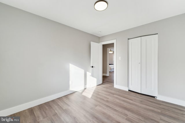 unfurnished bedroom featuring a closet, wood finished floors, and baseboards