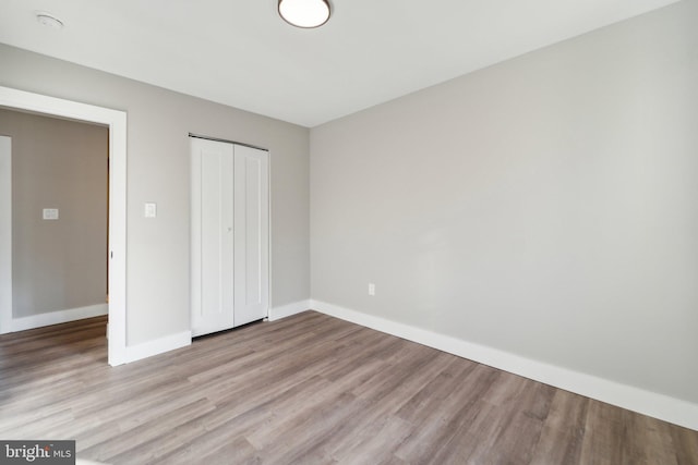 unfurnished bedroom with a closet, baseboards, and wood finished floors