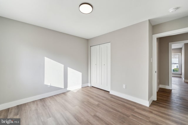 unfurnished bedroom with a closet, baseboards, and wood finished floors