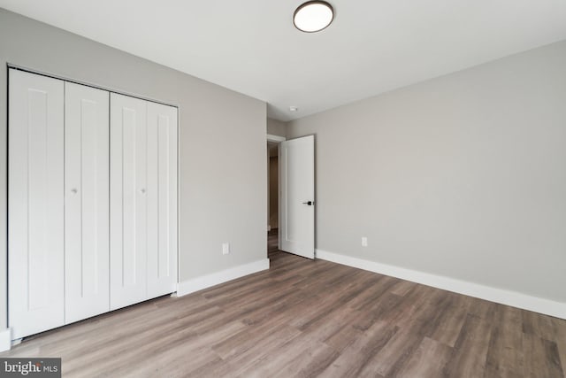 unfurnished bedroom featuring a closet, baseboards, and wood finished floors