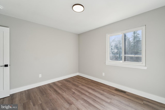 spare room featuring visible vents, baseboards, and wood finished floors