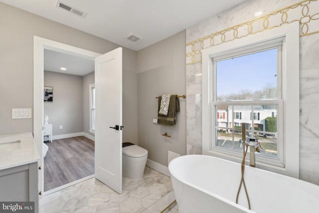 full bath featuring a soaking tub, visible vents, vanity, and marble finish floor