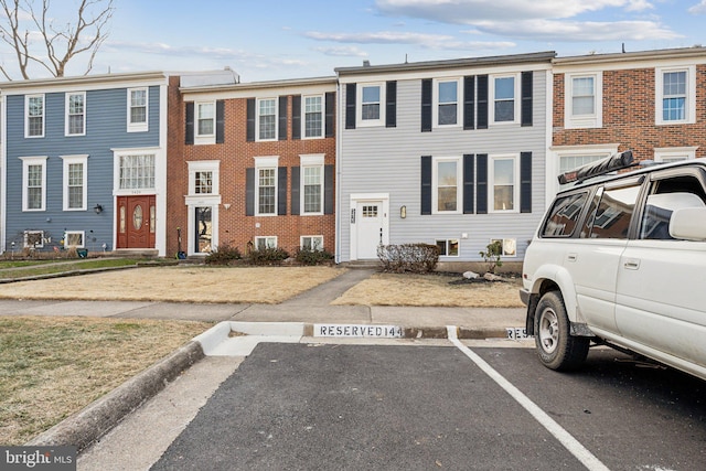 townhome / multi-family property featuring uncovered parking and brick siding