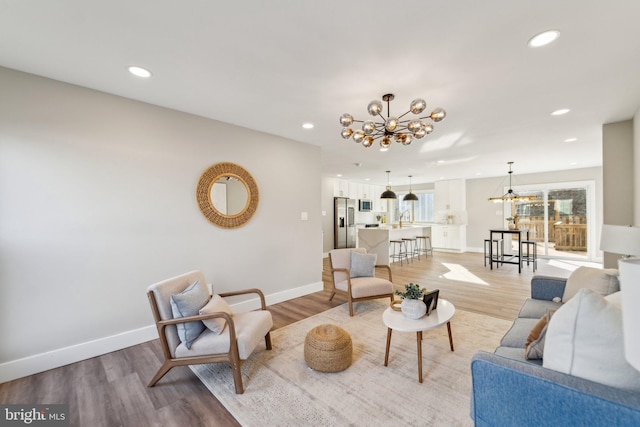 living area with light wood-style floors, baseboards, a chandelier, and recessed lighting